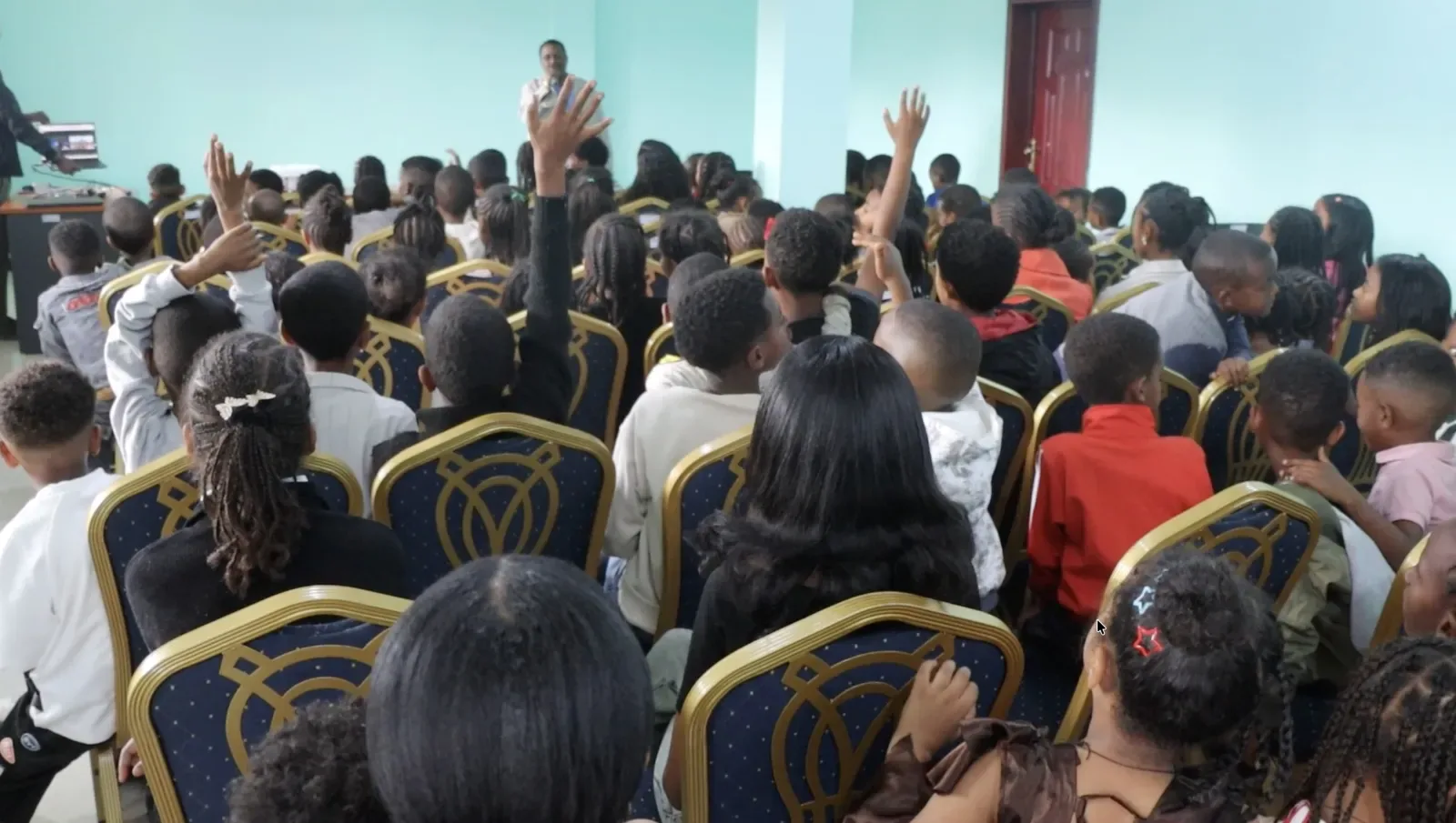 A hall full of students, hands raised, during one of EnlightenHMLA’s first events in Tigray